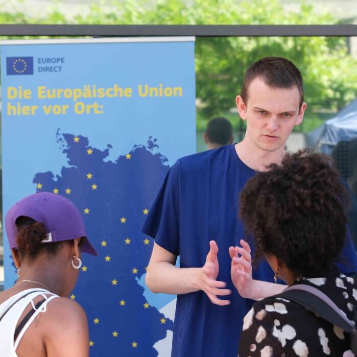 Ein junger Mann redet mit zwei Frauen über die Europäische Union